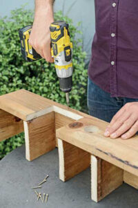 man using a drill on a cut portion of a wooden window box
